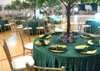 A spacious room featuring green tables and chairs arranged for group activities or meetings.
